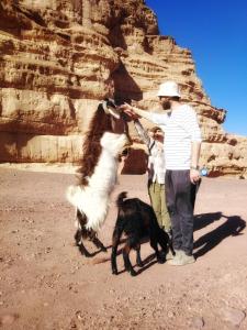 a man and a child and a goat in the desert at MalakoRum in El Quweira