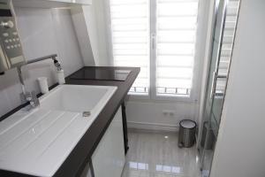 a white bathroom with a sink and a window at Studio Tour Eiffel in Paris