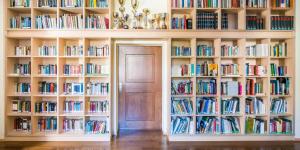 una habitación llena de estanterías llenas de libros en Haus Noldin - historische Herberge - dimora storica, en Salorno