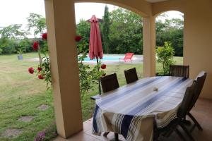 a table with chairs and an umbrella on a patio at Le Camp De Ferie in Monpazier