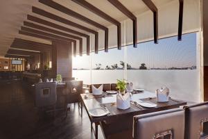 a dining room with tables and chairs and a large window at Whispering Palms Hotel Jaipur in Jaipur
