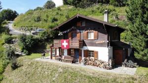Una casa su una collina con una croce rossa sopra di LUMA a Thyon-Les Collons