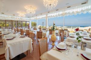 ベッラーリア・イジェア・マリーナにあるHotel Rosa Maria Eliteの海の景色を望む白いテーブルと椅子付きのレストラン