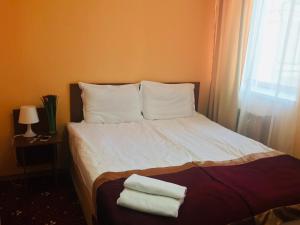 1 cama con sábanas y almohadas blancas y ventana en Davidov Inn en Kazán