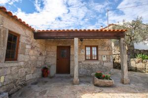 uma casa de pedra com uma porta de madeira e um alpendre em Casas da Lagaria em Sortelha
