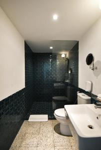 a black tiled bathroom with a toilet and a sink at Hotel Monopoli in Jakarta
