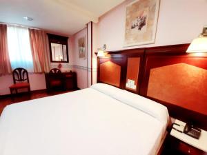 Habitación de hotel con cama con cabecero de madera en Hosteria Sara by gaiarooms, en Salamanca