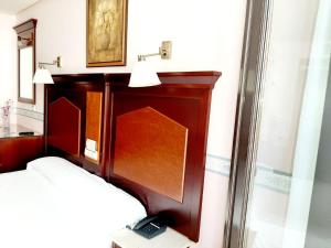 Schlafzimmer mit einem Bett und einem Kopfteil aus Holz in der Unterkunft Hosteria Sara by gaiarooms in Salamanca