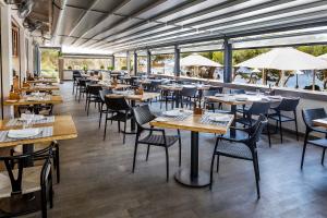 um restaurante com mesas, cadeiras e janelas em Catalonia Ses Estaques - Adults Only em Santa Eulária des Riu