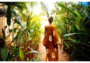 a woman walking down a path through a garden at Anahata Retreat Sea Front Resort Ashvem in Mandrem