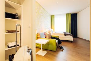 ein Hotelzimmer mit einem Bett und einem Sofa in der Unterkunft harry's home hotel & apartments in Dornbirn