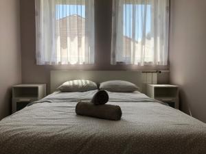 uma cama com uma almofada com duas janelas em Balian apartman em Siófok