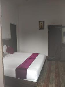 a bedroom with a white bed with a purple blanket on it at Landy Queen in Munnar