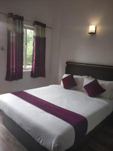a bed with purple and white sheets and a window at Landy Queen in Munnar
