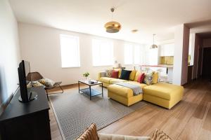sala de estar con 2 sofás amarillos y cocina en Chez Emile Private 5 star 3 room flat and in-door Pkg, en Nitra