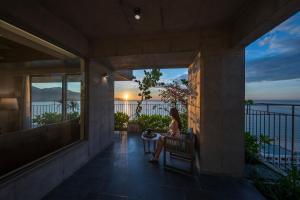 a woman sitting on a balcony watching the sunset at Chicland Danang Beach Hotel in Da Nang