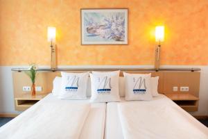 Habitación de hotel con cama con almohadas blancas en Miratel, en Mitterteich