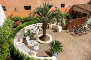 an outdoor patio with tables and chairs and a palm tree at Palm Suites - Small Luxury Hotels of the World in Rome
