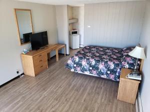 1 dormitorio con 1 cama y escritorio con TV en Rainbow Motel, en Swift Current