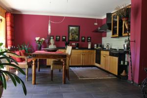 ModautalにあるFeWo - Wohlfühlambiente & Gartenparadiesの赤い壁のキッチン(木製テーブル付)