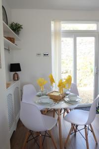 a white dining room with a table and chairs at 1 Saron Cottages in Llandudno