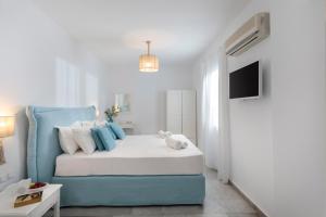 1 dormitorio blanco y azul con 1 cama y TV en Ippokampos Town Apartments, en Naxos Chora