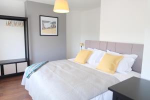 1 dormitorio con 1 cama blanca grande con almohadas amarillas en 1 Saron Cottages, en Llandudno