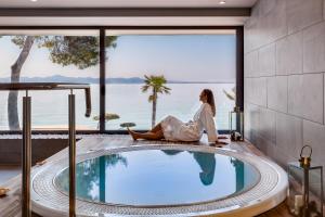 a woman sitting next to a swimming pool in a hotel room at Hotel Pinija in Petrcane