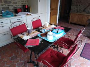 a table with red chairs in a kitchen at L'Tas De Cailloux in Cancale +6 photos