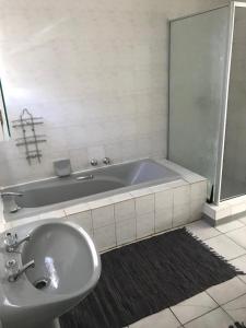 Baño blanco con bañera y lavamanos en Tortilla no 3, en Bloemfontein
