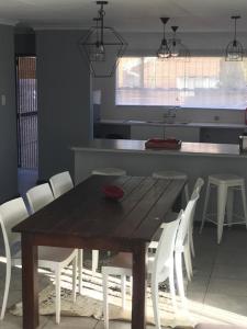 einen Holztisch und weiße Stühle in der Küche in der Unterkunft Tortilla no 3 in Bloemfontein