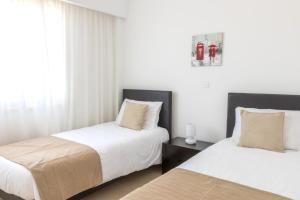 two beds in a room with white walls at Elysia Park in Paphos