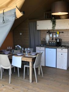 uma cozinha com uma mesa e cadeiras de madeira e uma cozinha com um balcão em Glamping Tuscany - Podere Cortesi em Santa Luce