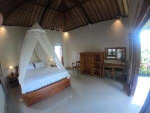 a bedroom with a bed with a mosquito net at Rumah Sidemen in Sidemen
