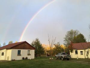 Ein Regenbogen am Himmel über einem Haus mit einem Truck in der Unterkunft Landhof-Erkner in Erkner