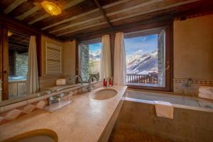 a bathroom with a large tub and a large window at Relais Mont Blanc Hotel & Spa in La Salle