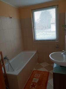 baño con bañera, lavabo y ventana en Landhof-Erkner, en Erkner