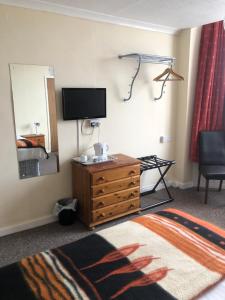 a hotel room with a television and a dresser with a mirror at The Hunt Lodge in Leighton Buzzard