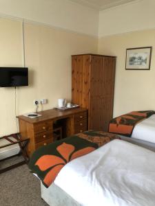 a hotel room with two beds and a desk and a sink at The Hunt Lodge in Leighton Buzzard