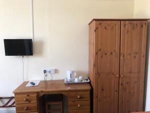 a small room with a wooden dresser and a television at The Hunt Lodge in Leighton Buzzard
