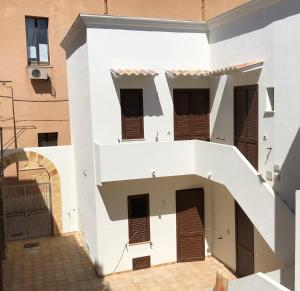a white building with brown shutters and a staircase at Casa Vacanze Antico Mercato in Marsala