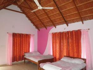 Cette chambre comprend deux lits et un ventilateur de plafond. dans l'établissement Vamoose Clover Leaf, à Chikmagalur