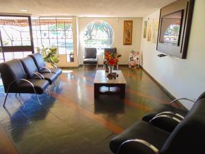 una sala de espera con sillas de cuero y mesa de centro en Hotel Damen, en Foz do Iguaçu
