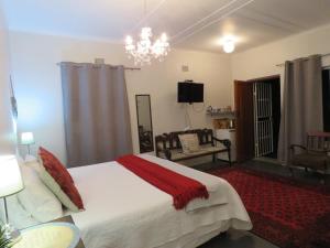 a bedroom with a large bed and a chandelier at Koraalboom in Wolseley