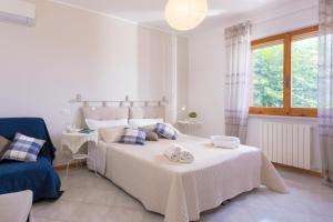 a white bedroom with two beds and a chair at Abbadia 14 in Osimo