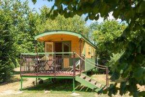 una pequeña casa amarilla y verde con porche en Rives Nature en La Gacilly