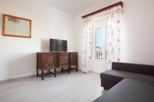 een woonkamer met een tv, een bank en een raam bij Akira Flats Cadaqués Llané in Cadaqués