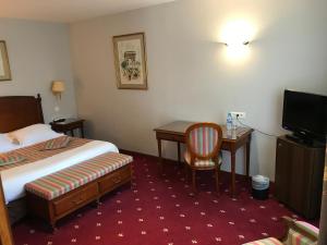 Habitación de hotel con cama, escritorio y TV. en Château de Sancy, en Sancy-lès-Meaux