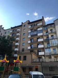 un gran edificio de apartamentos con un parque infantil delante de él en Нові Апартаменти, en Lyubomirka
