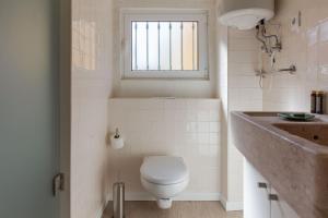 baño con aseo y lavabo y ventana en Typical and Brand New T.M. Flat, en Lisboa